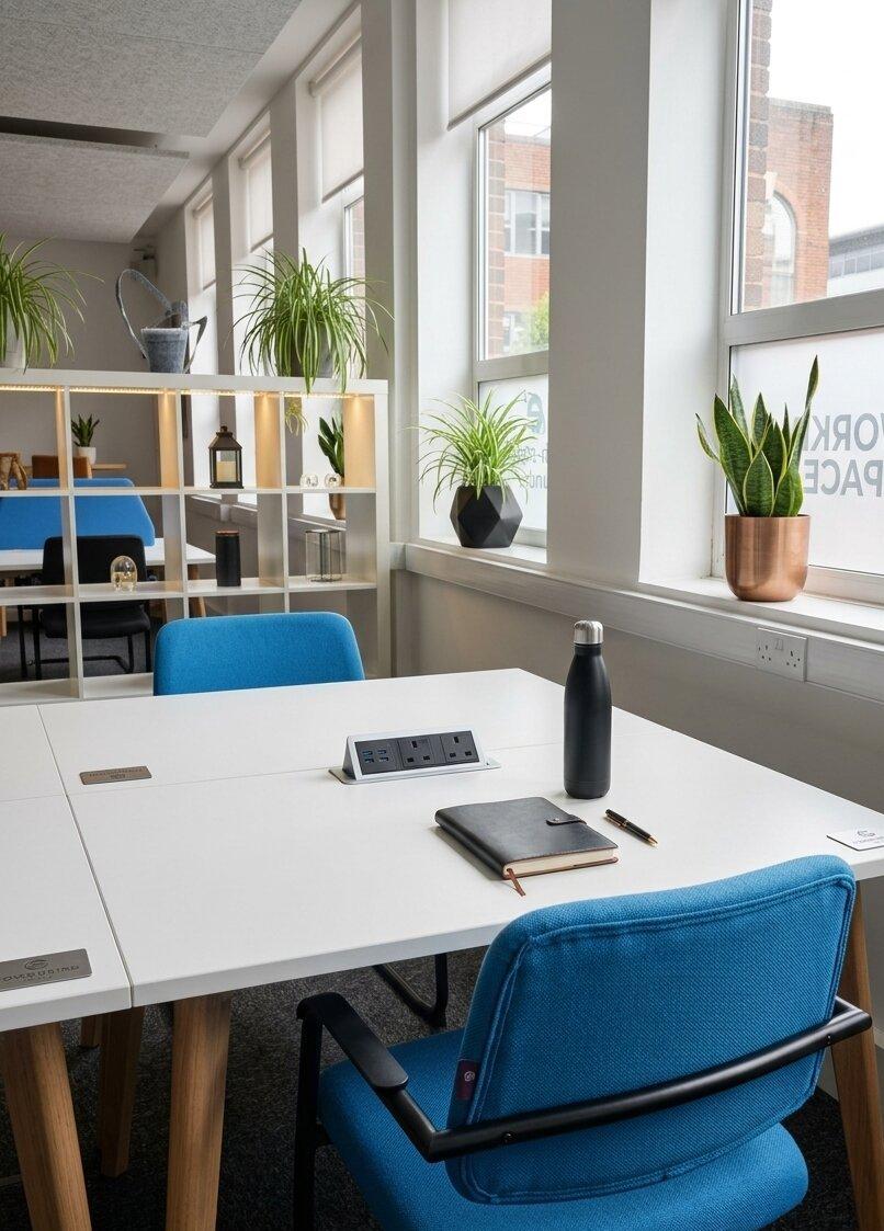 A bright hot desk area at Worcester Coworking with plants and natural light